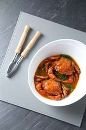 Delicious boiled crabs with sauce and cracker on grey table, top view