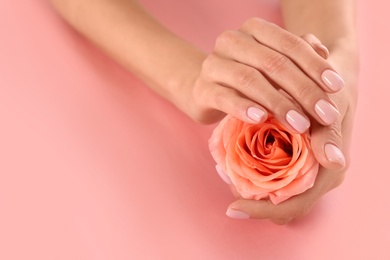 Closeup view of woman with rose on color background, space for text. Spa treatment