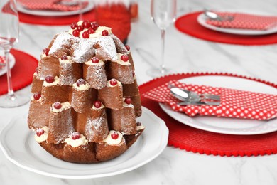 Delicious Pandoro Christmas tree cake decorated with powdered sugar and berries on white marble table