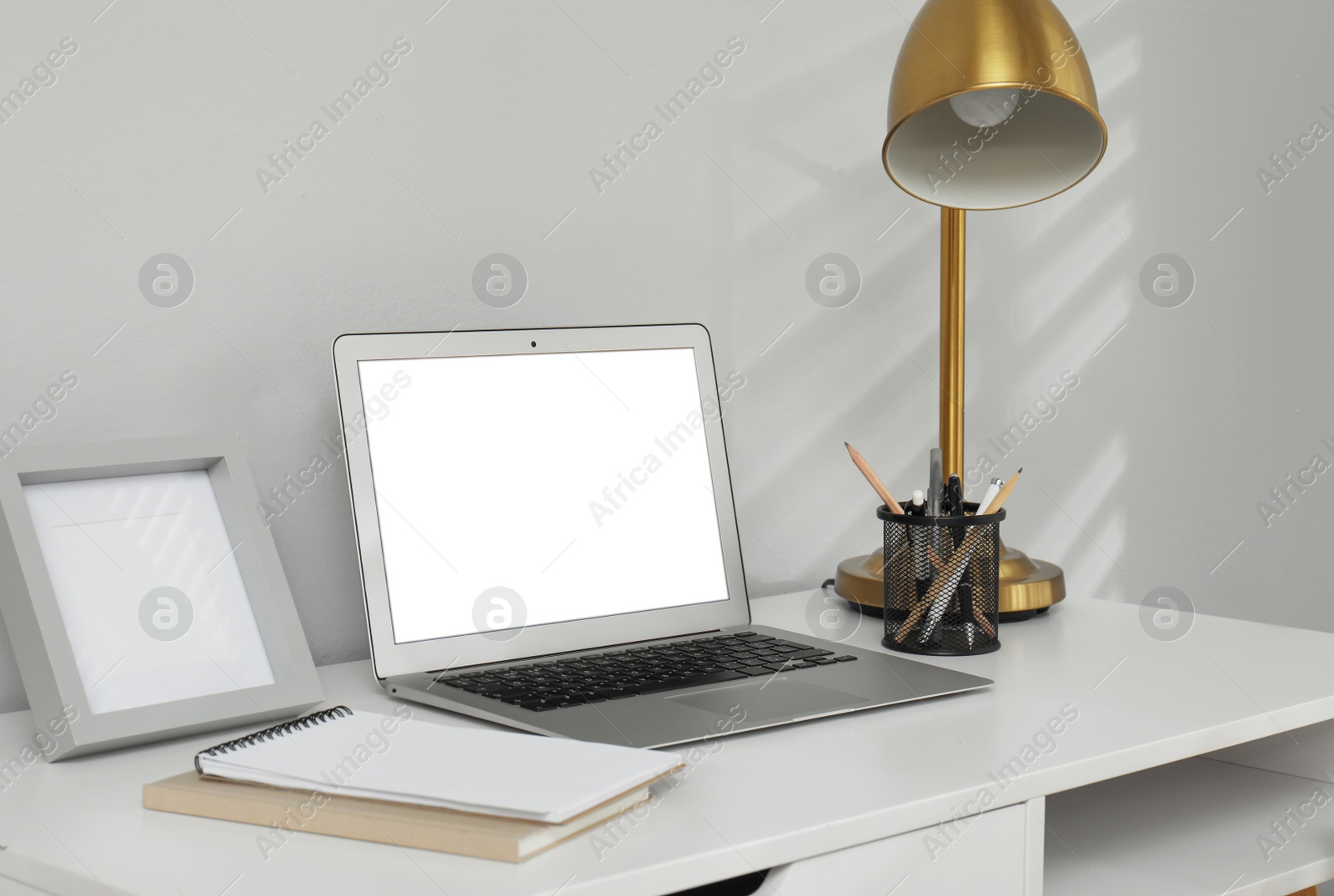 Photo of Comfortable workplace with modern laptop near light grey wall indoors. Space for design