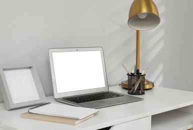 Photo of Comfortable workplace with modern laptop near light grey wall indoors. Space for design