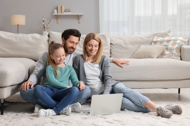 Photo of Happy family with laptop on floor at home
