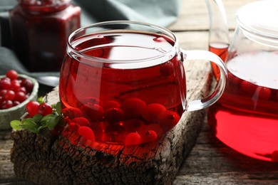 Photo of Delicious cranberry tea and berries on wooden table, closeup