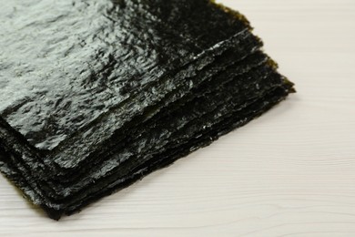 Stack of dry nori sheets on white wooden table, closeup. Space for text