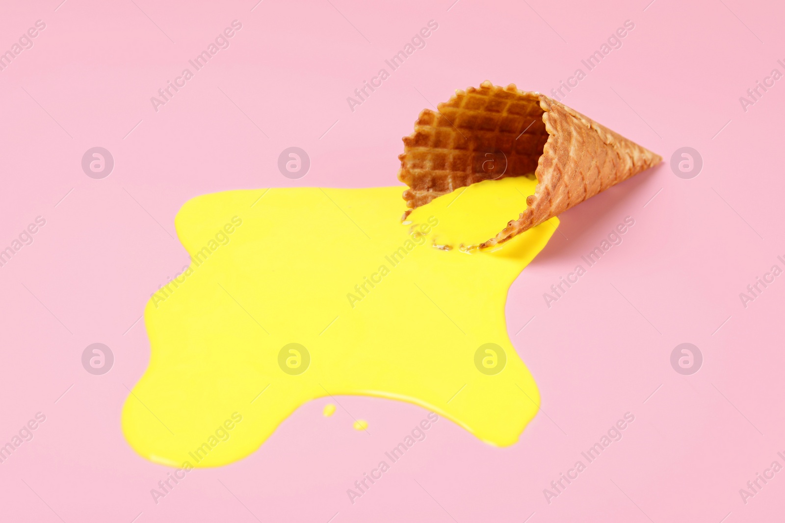 Photo of Melted ice cream and wafer cone on pink background