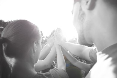 Image of Group of volunteers joining hands together outdoors. Black and white effect