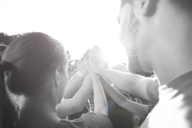 Group of volunteers joining hands together outdoors. Black and white effect