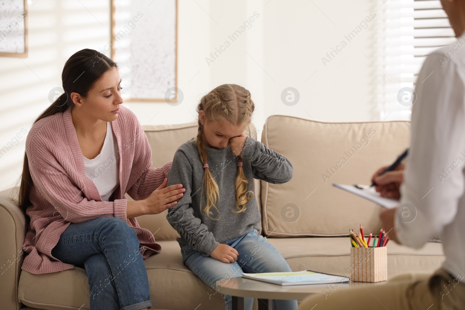 Photo of Little girl and her mother on appointment with child psychotherapist indoors