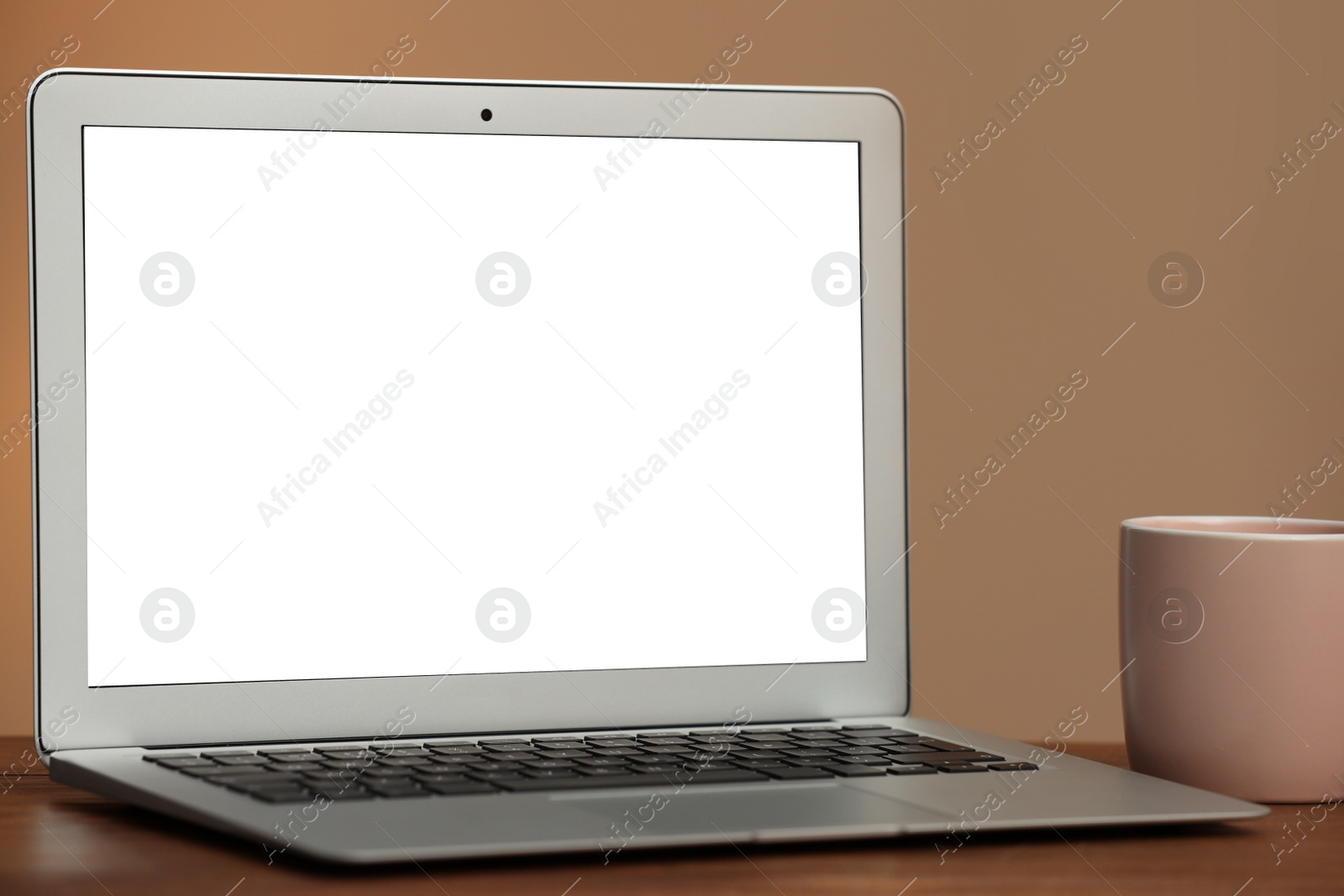 Photo of Laptop with blank screen on table indoors. Space for text