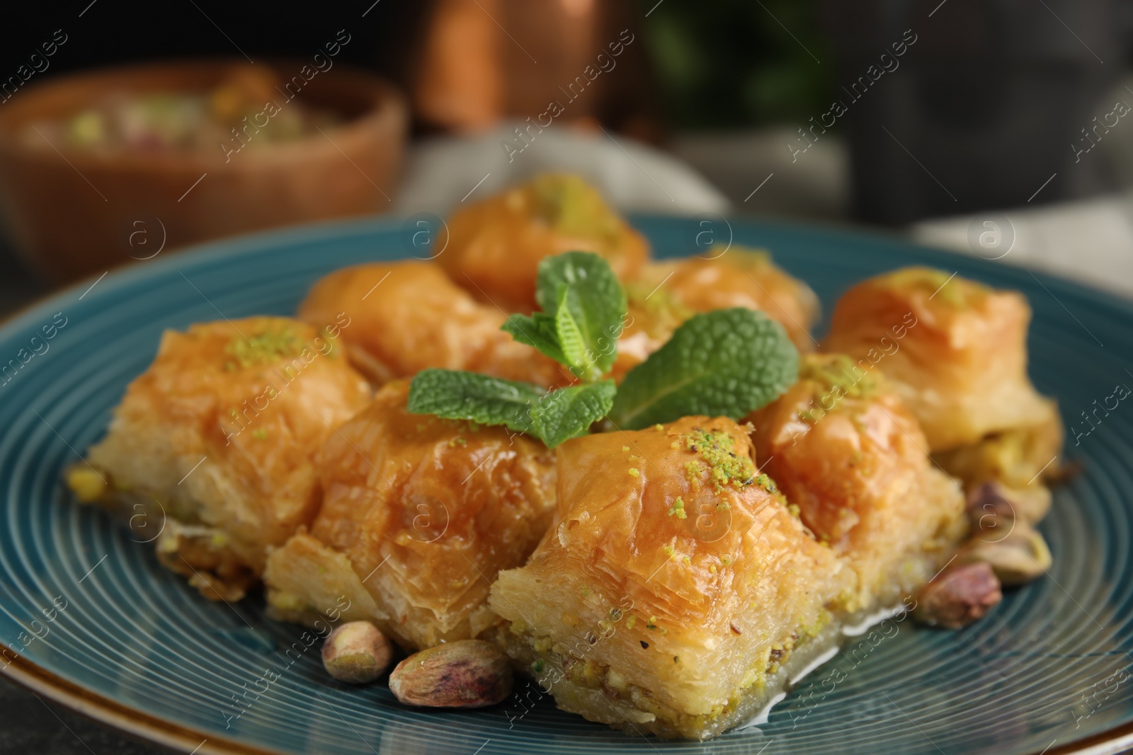 Photo of Delicious baklava with pistachio nuts and mint on plate, closeup