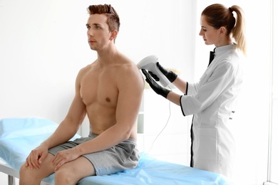 Photo of Man undergoing hair removal procedure with photo epilator in salon
