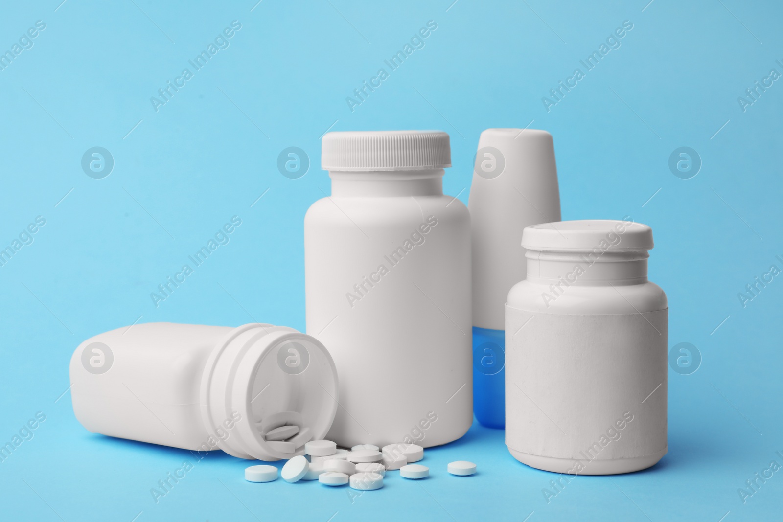 Photo of Containers and scattered pills on color background