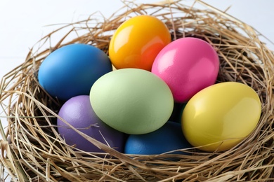 Photo of Bright painted eggs in nest, closeup. Happy Easter