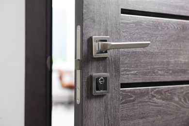 Photo of Open wooden door with metal handle, closeup