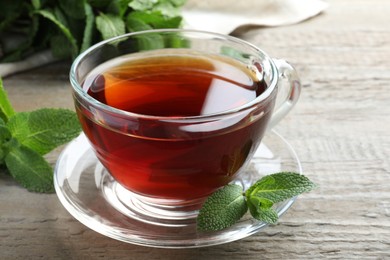 Cup of hot aromatic tea with mint on wooden table, closeup