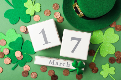 Flat lay composition with wooden block calendar on green background. St. Patrick's Day celebration