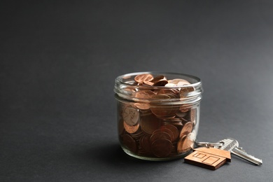 Photo of Glass jar with coins and house key on black background. Space for text