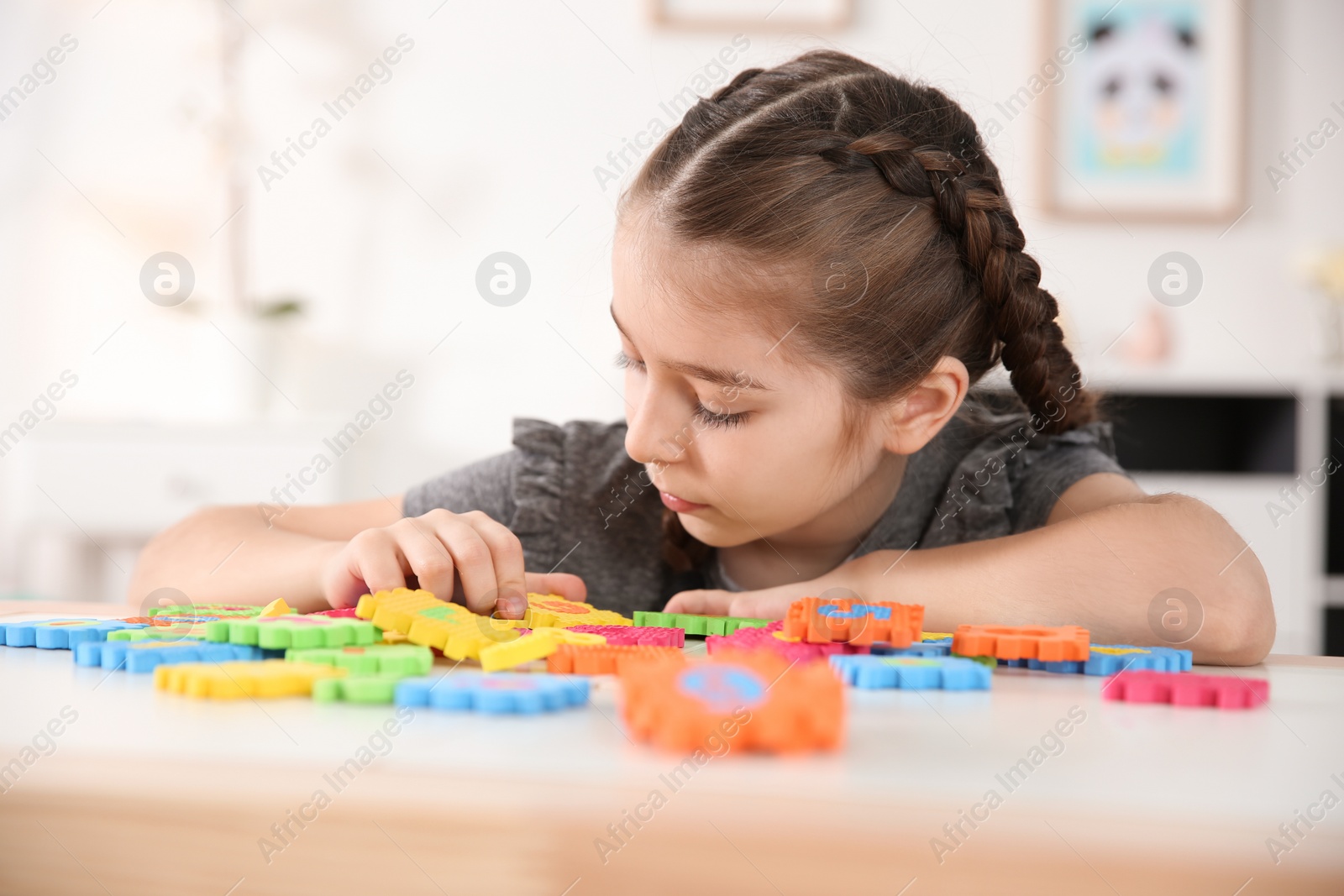 Photo of Little autistic girl playing with puzzles at home