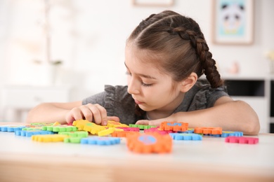 Photo of Little autistic girl playing with puzzles at home