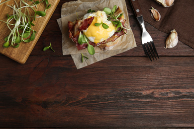 Photo of Delicious egg Benedict served on wooden table, flat lay. Space for text