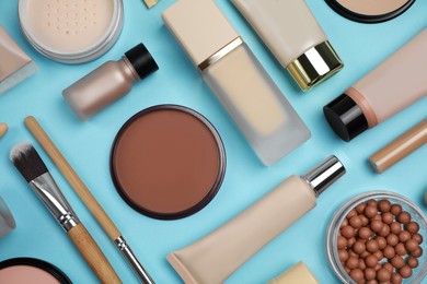 Photo of Face powders and other decorative cosmetic products on light blue background, flat lay