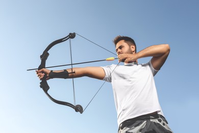 Photo of Man with bow and arrow practicing archery outdoors, low angle view