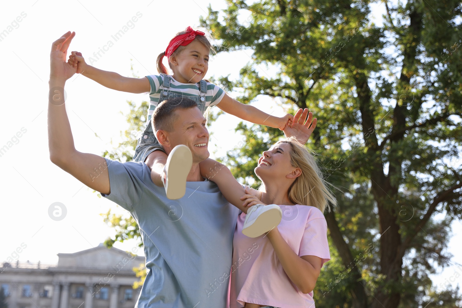 Photo of Happy parents with their child having fun at park. Spending time in nature