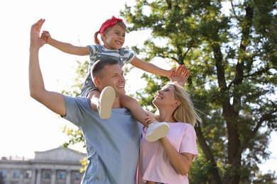 Photo of Happy parents with their child having fun at park. Spending time in nature