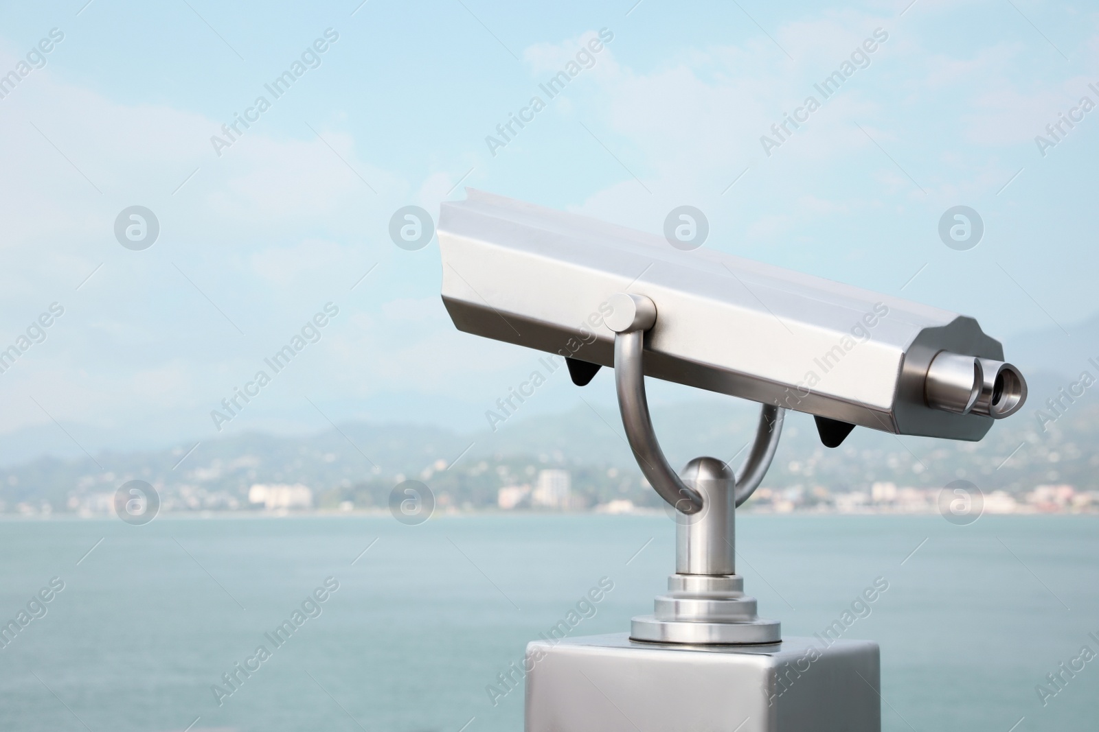 Photo of Metal tower viewer installed near sea, space for text. Mounted binoculars