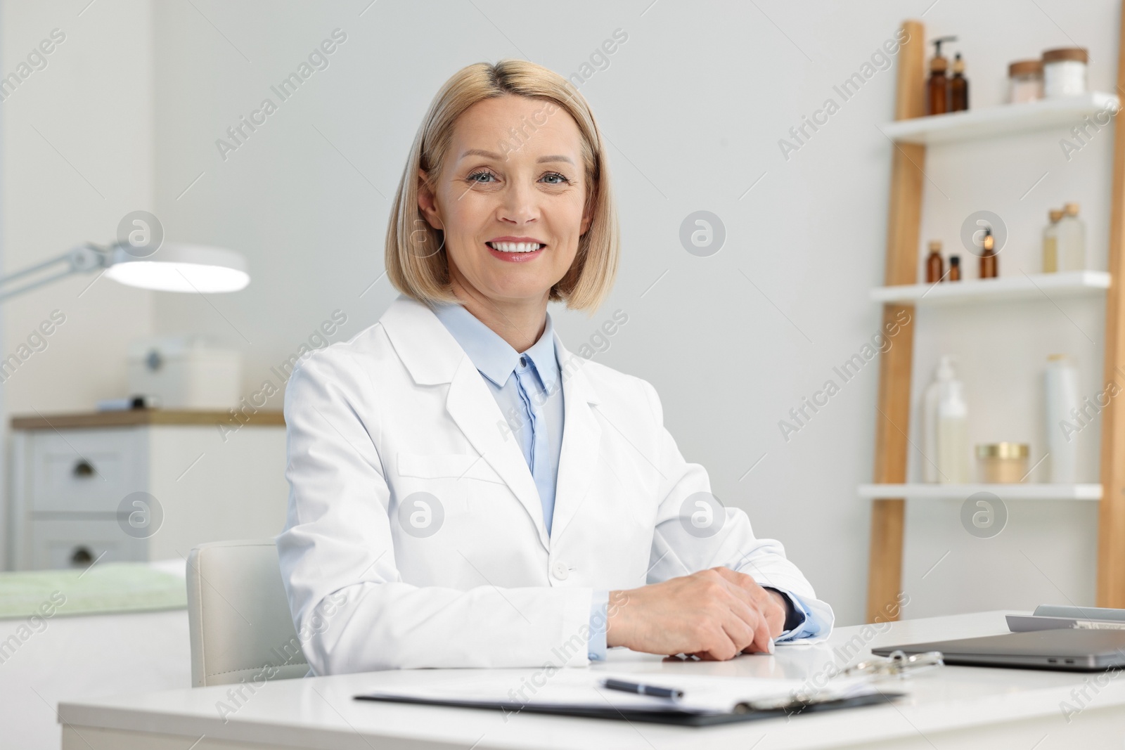 Photo of Portrait of happy dermatologist at white table in clinic