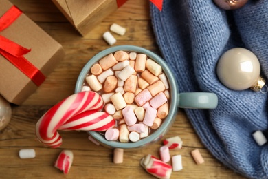 Photo of Flat lay composition with cup of tasty cocoa, candy canes and Christmas gifts on wooden table, flat lay