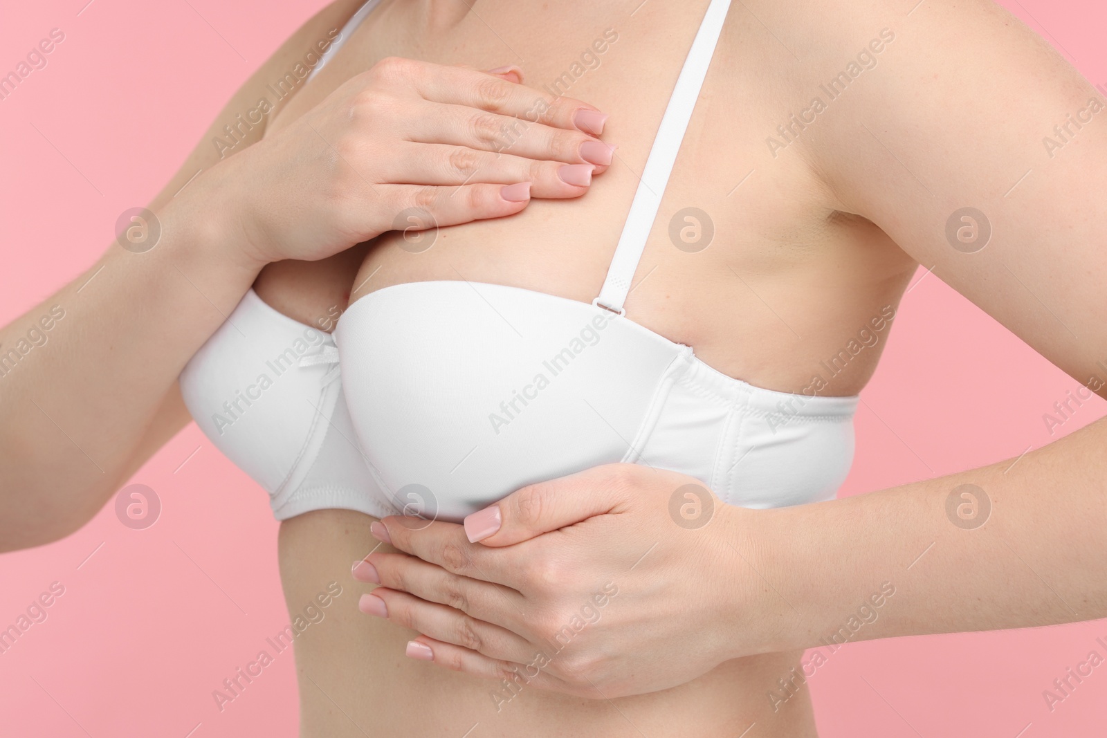 Photo of Mammology. Young woman doing breast self-examination on pink background, closeup