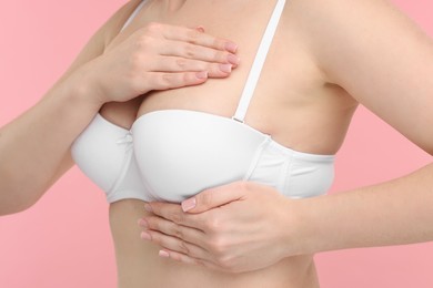 Mammology. Young woman doing breast self-examination on pink background, closeup