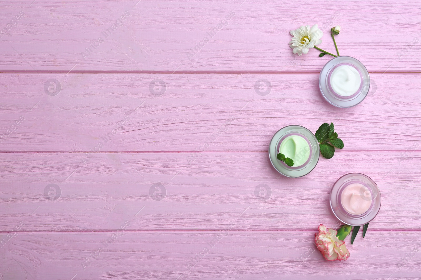 Photo of Jars with body cream on wooden background