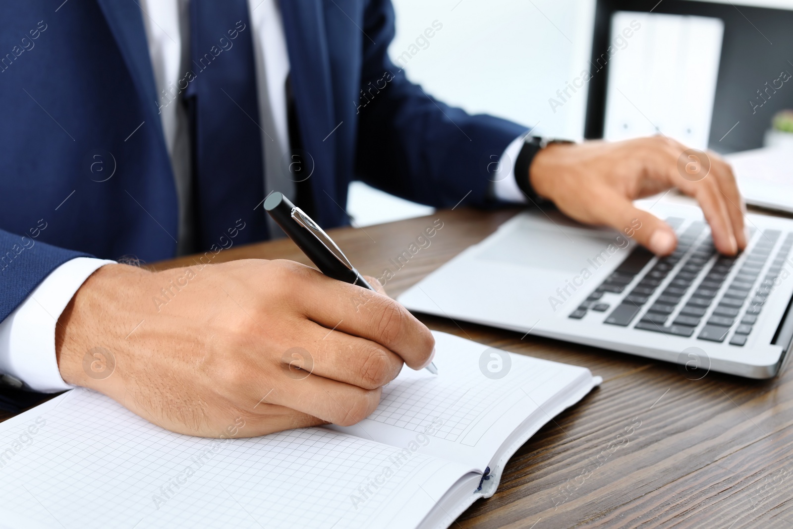 Photo of Lawyer working with laptop and notebook at table, closeup