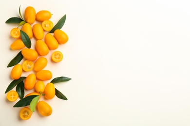 Photo of Fresh ripe kumquats with green leaves on white background, flat lay. Space for text