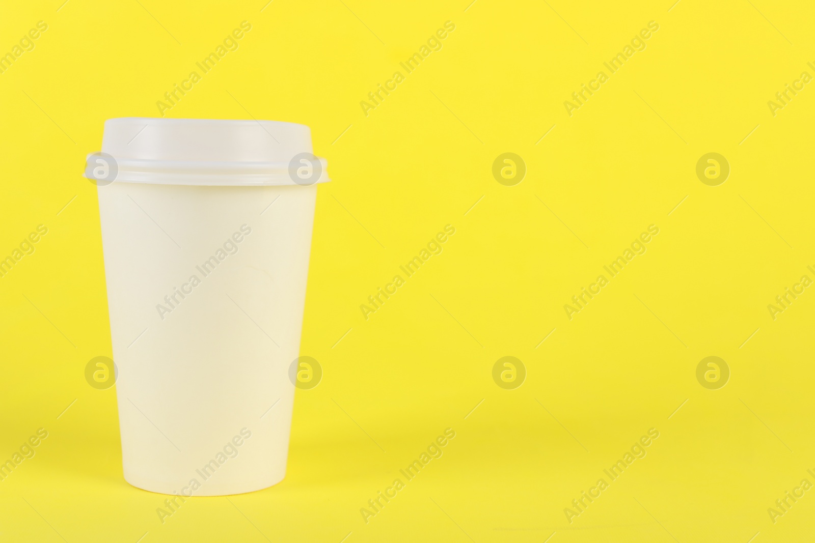 Photo of Paper cup with plastic lid on yellow background, space for text. Coffee to go