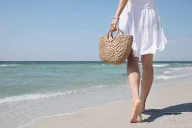 Woman with beach bag walking near sea, closeup