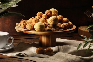 Photo of Aromatic walnut shaped cookies and tea on wooden table. Homemade pastry carrying nostalgic atmosphere