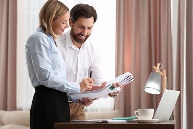 Photo of Happy businesspeople working with documents in office