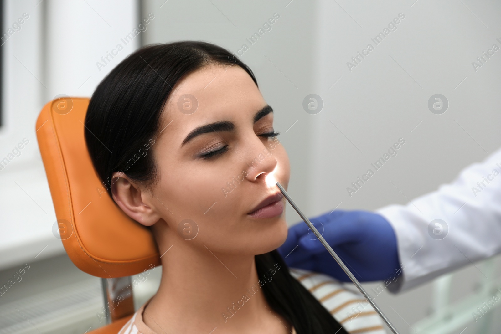 Photo of Doctor examining patient with modern equipment before nasal surgery in clinic