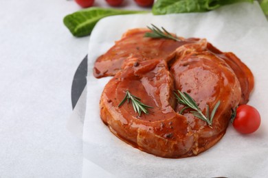 Photo of Raw marinated meat and rosemary on light table, closeup. Space for text