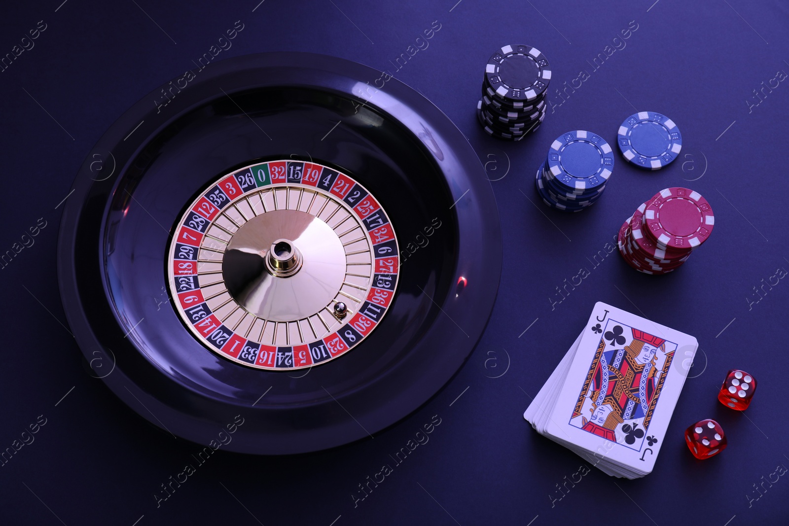 Photo of Roulette wheel, playing cards and chips on table, flat lay. Casino game