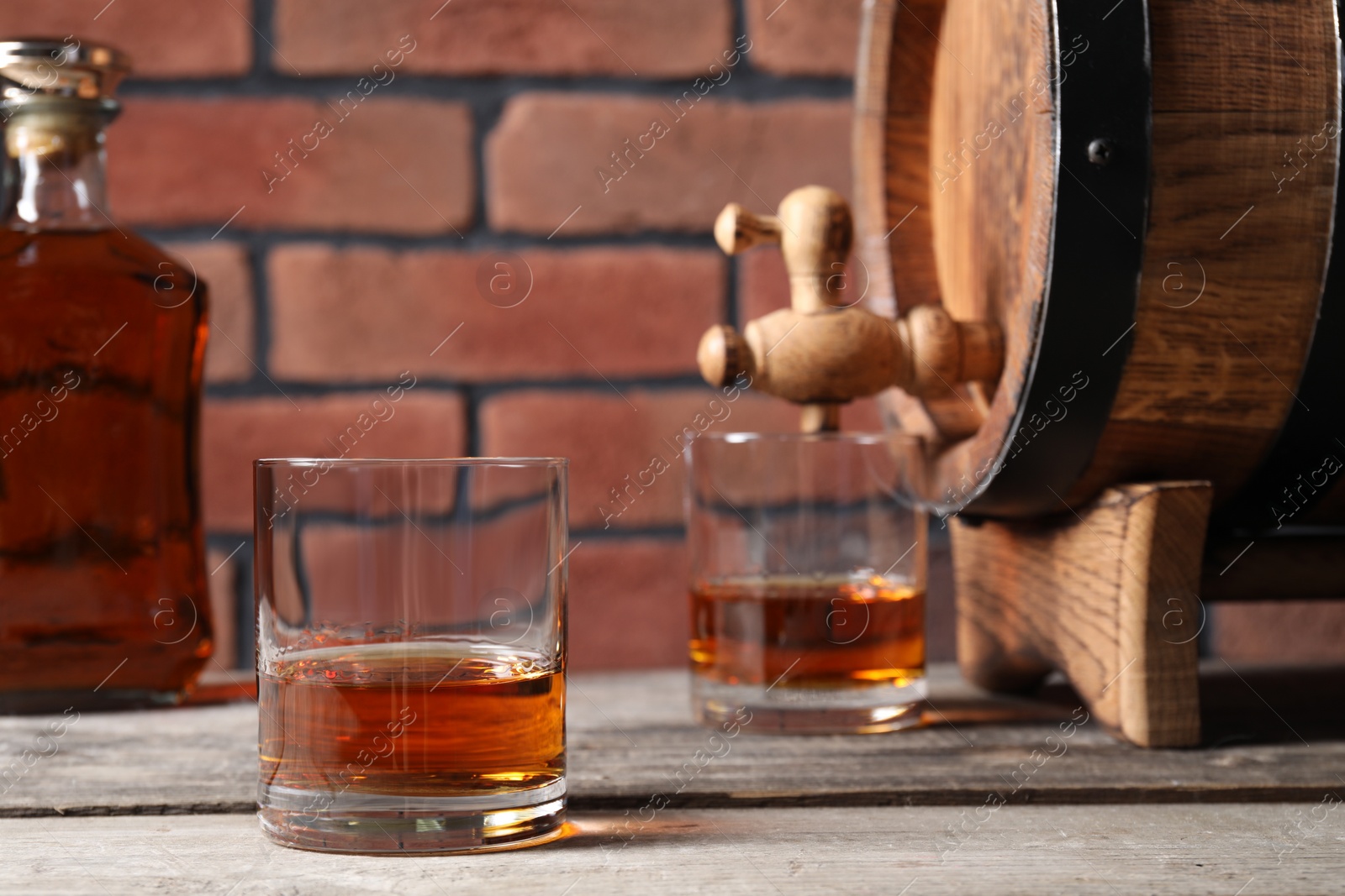 Photo of Glasses of whiskey and wooden barrel on table