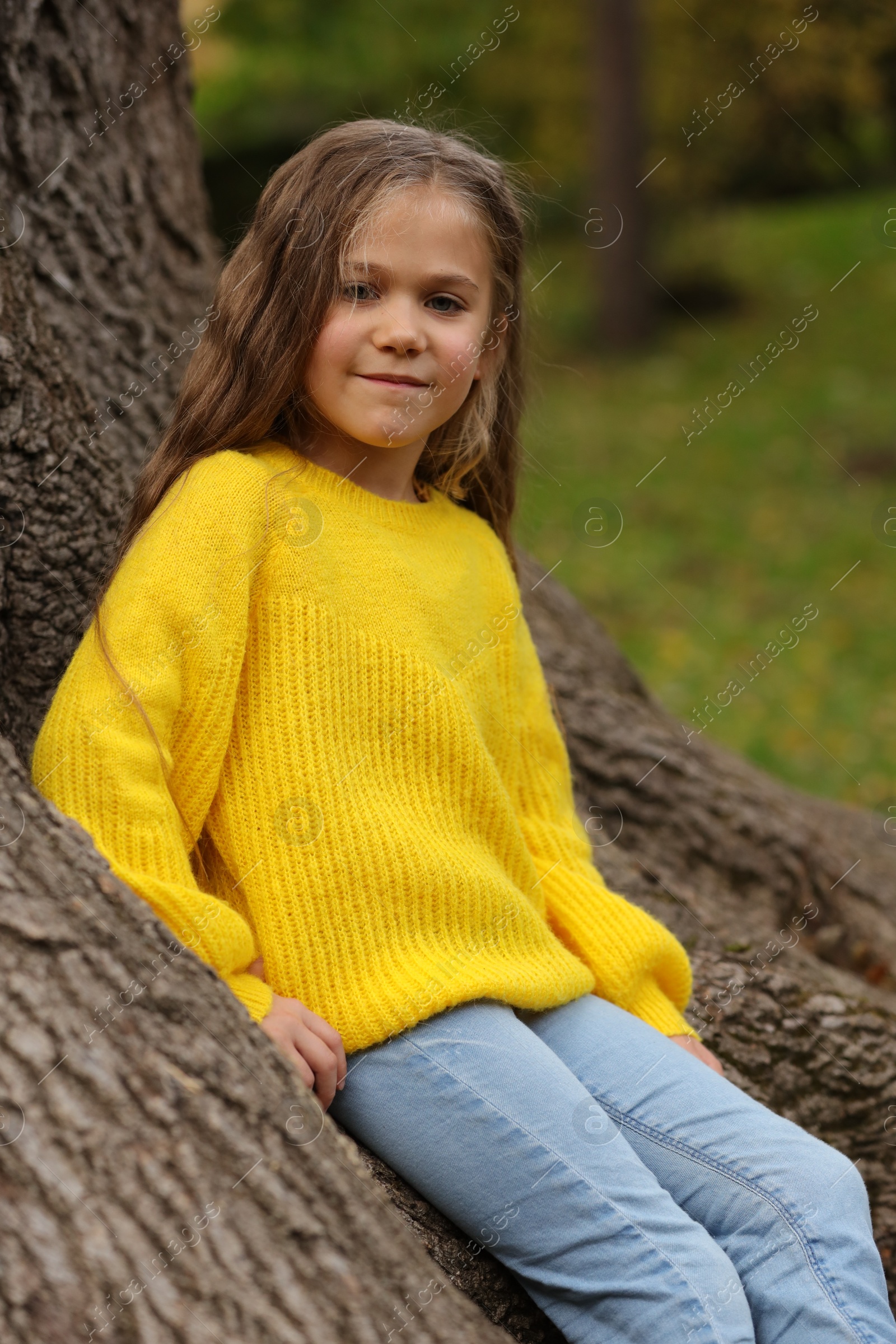 Photo of Portrait of cute girl near tree in autumn park