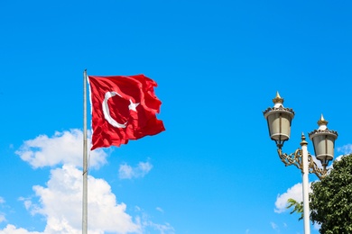 Photo of Turkish flag fluttering on blue sky background