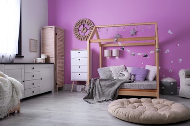 Photo of Child's room interior with comfortable bed and garland