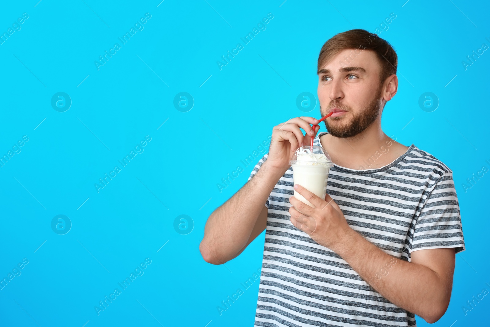 Photo of Young man with cup of delicious milk shake on color background