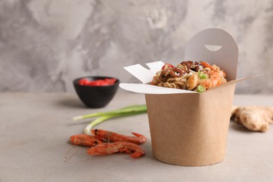 Box of wok noodles with seafood on light table. Space for text