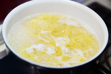 Cooking pasta in saucepan on stove, closeup